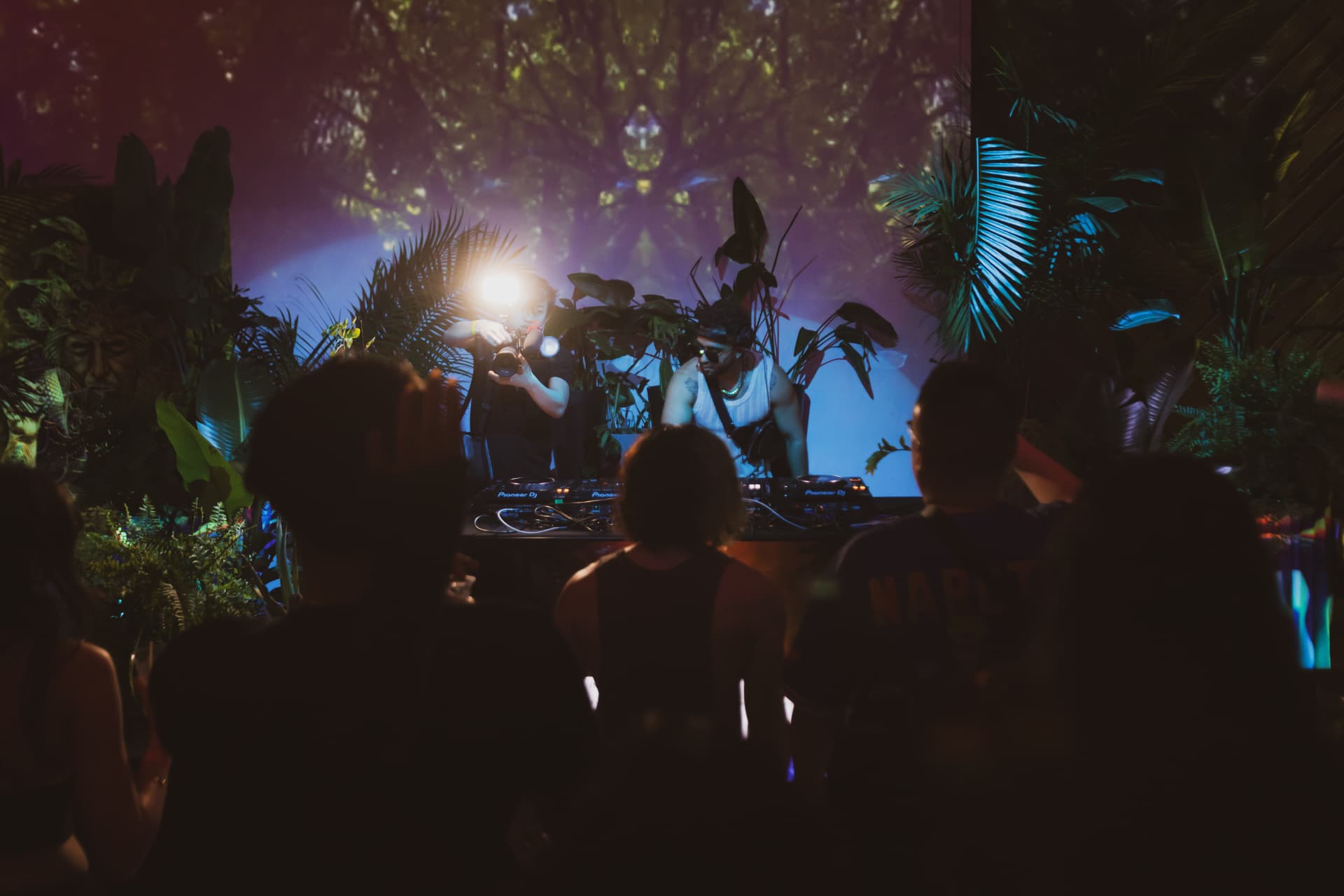 The booth seen through the crowd in the plant-filled room